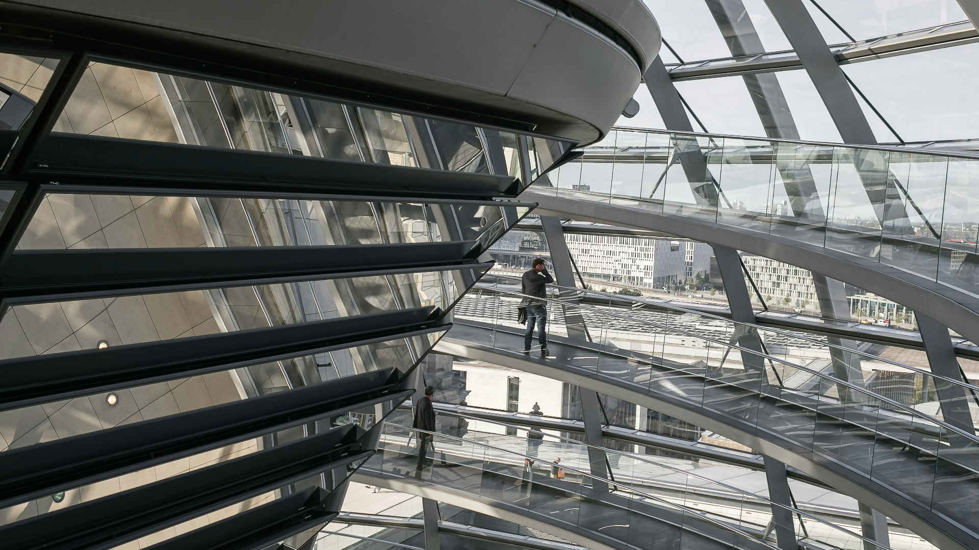 People moving through the walkways of a large glass and steel structure.