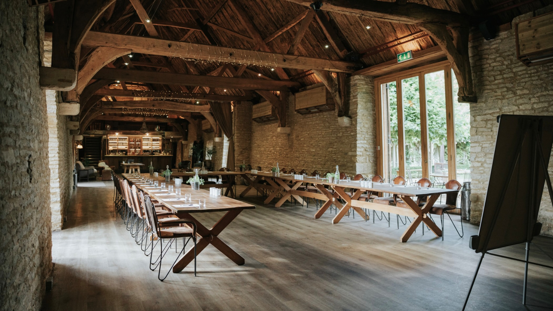 A converted barn set up for a team offsite, with exposed beams and daylight through garden doors.